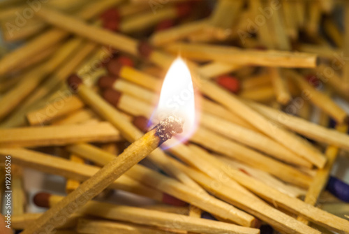 match sticks spread on white paper and match burning in center abstract photo