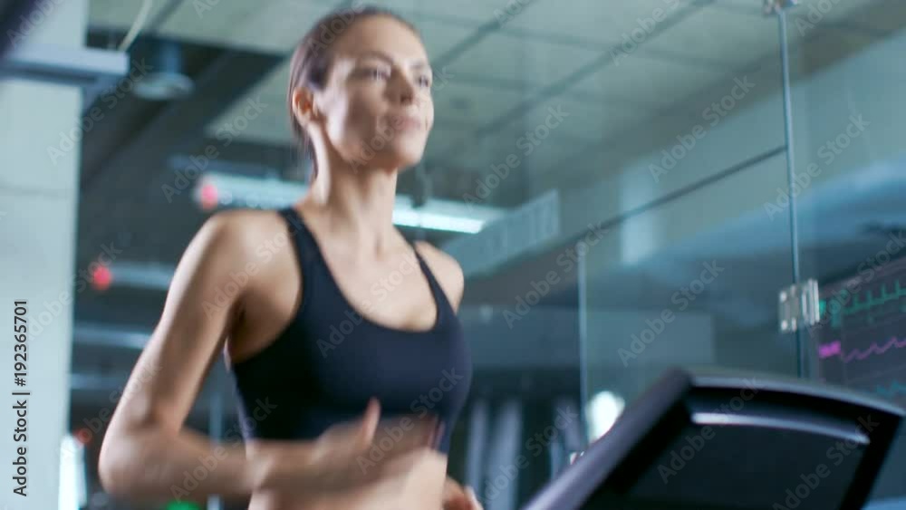 Beautiful Woman Athlete Wearing Sport Bra, Walks on a Treadmill, Training Exercise. In the Background Modern Gym/ Fitness Club. Beautiful Woman Athlete Wearing Sport Bra, Walks on a Treadmill, Training Exercise. In the Background Modern Gym/ Fitness Club.