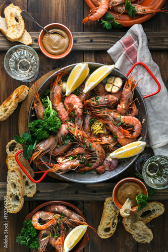 Paella pan with roasted tiger prawns and many dishes, bread and wine