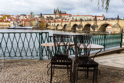 Photography Panorama with Table and chairs of cafe on background Prague castle and river Vlt