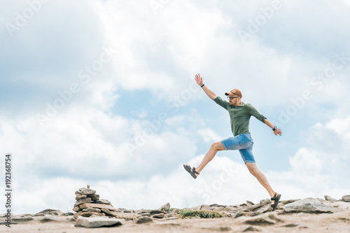 Sport activity at top of mountain. Professional sporstman jumping forward outdoor at nature. Conquering new mountains. Overcoming progress. Summer fun. Unusual traveler stepping stones. Successful boy