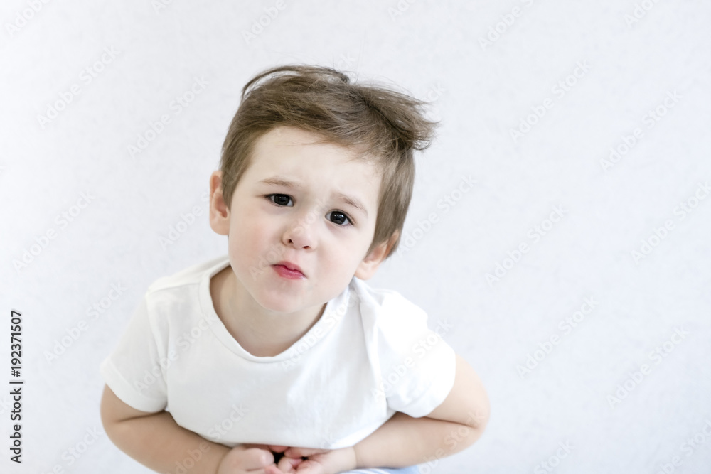 Caucasian little boy with stomach ache, child holding his hands on his