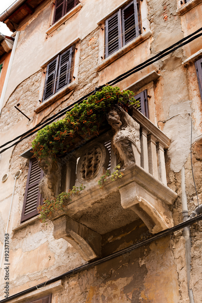 Facade of an old house with a stone balcony decorated with lion heads