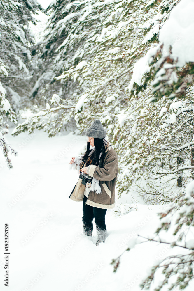 A beautiful girl walks through the snowy winter coniferous forest.
