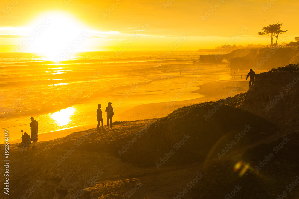 People enjoying the view of a stunningly colorful sunset in Santa Cruz, California in winter