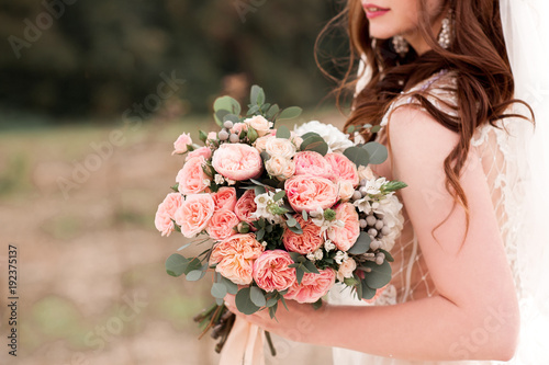 Bride holding flowers outdoors close up. Wedding day. 20s.