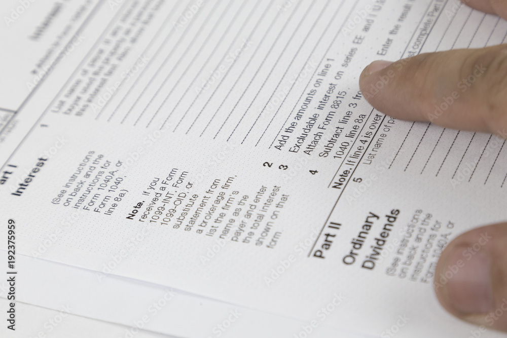 Tax concept. Man looking through US tax form with hands Tax concept. Man looking through US tax form with hands