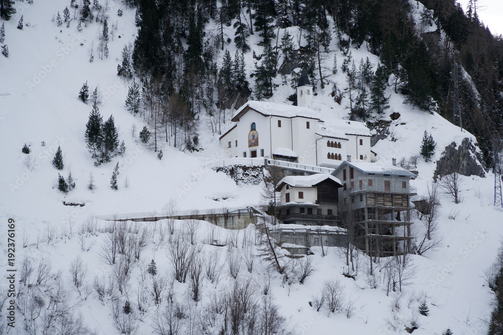 Church in mountains covered with snow and winter forest near Mont Blanc Alpes, Italy