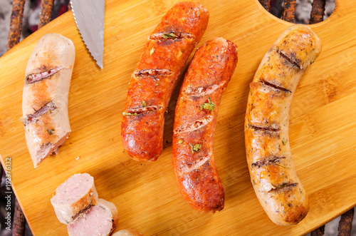Close up of grilled sausages on wooden cutting board, BBQ in the garden. Bavarian sausages
