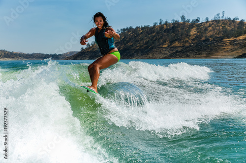 Mixed race fit young woman wakesurfing on a lake in California on a clear summer day photo