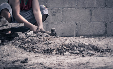 Child working with hammer at construction site for child labor and human rights concept