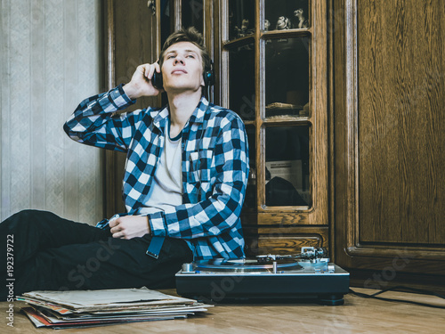 portrait of young man at home listening to the vinyl records, relaxing and dreaning photo