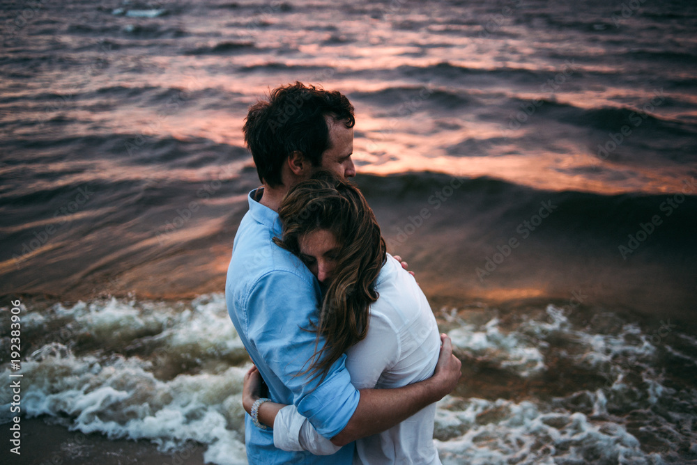 Romantic photo on which a couple in love stands on the seashore at sunset and embracing