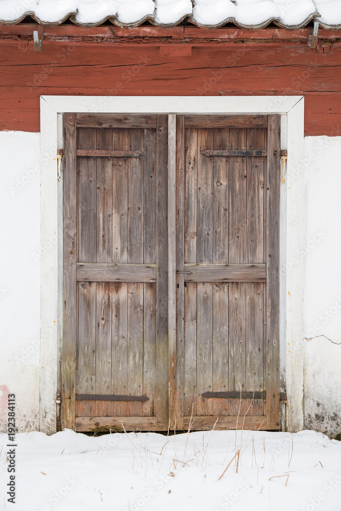 Old wooden doors on a white house with snow in front Old wooden doors on a white house with snow in front