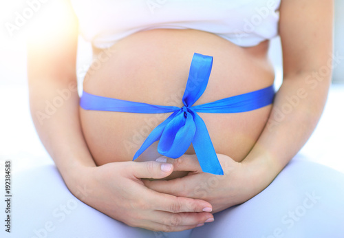 Wallpaper Mural closeup of a pregnant woman tying a blue ribbon on her belly Torontodigital.ca