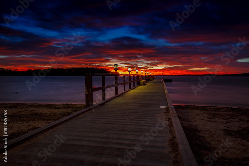 Long jetty with light at a colorful sunset