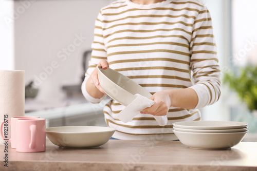Obraz na płótnie Woman wiping dishware with paper towel in kitchen