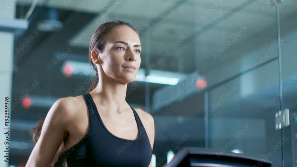In Scientific Sports Laboratory Beautiful Woman Athlete Walks on a Treadmill with Electrodes Attached to Her Body, Monitors Show EKG Data on Display. Slow Motion. Low Angle. In Scientific Sports Laboratory Beautiful Woman Athlete Walks on a Treadmill with Electrodes Attached to Her Body, Monitors Show EKG Data on Display. Slow Motion. Low Angle.