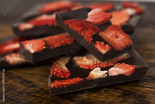 Stack of chocolate slices with strawberry on wooden background