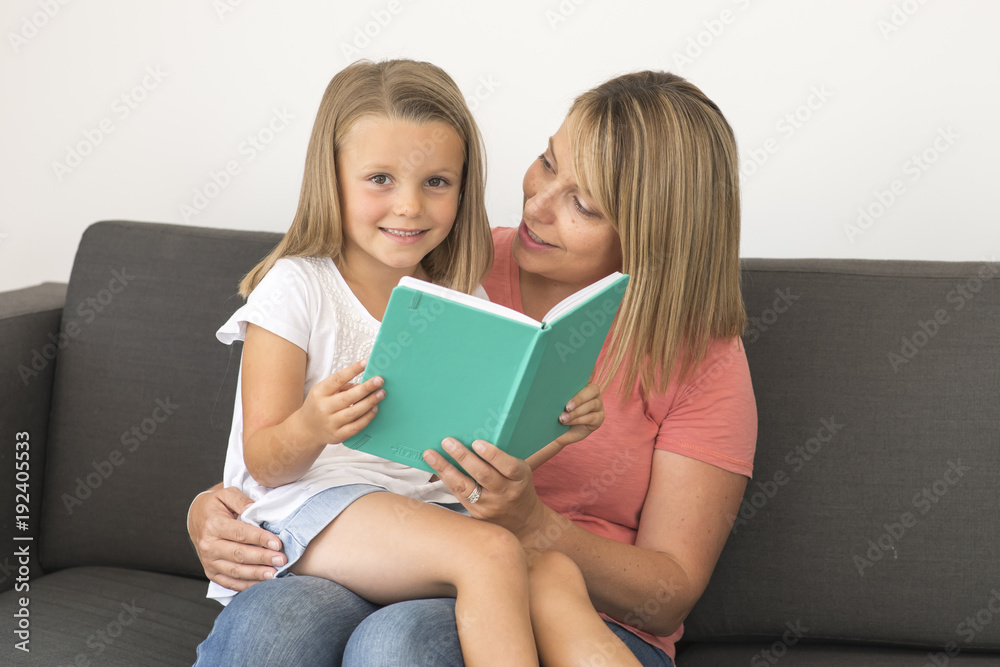 young beautiful and happy women sitting together with her adorable 7 years old adorable blond girl reading book enjoying telling story