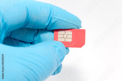 hand in blue glove holding sim card on white background