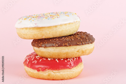 Three donuts with icing on pink background. Sweet donuts.