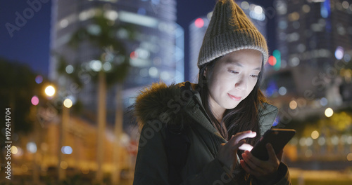 Canvas Print Woman wearing winter jacket and using cellphone at night