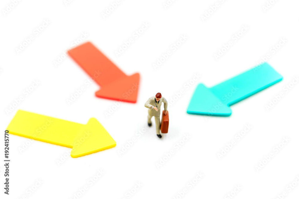 Miniature people: Businessman standing in front of arrow pathway choice using as Business decision concept Miniature people: Businessman standing in front of arrow pathway choice using as Business decision concept
