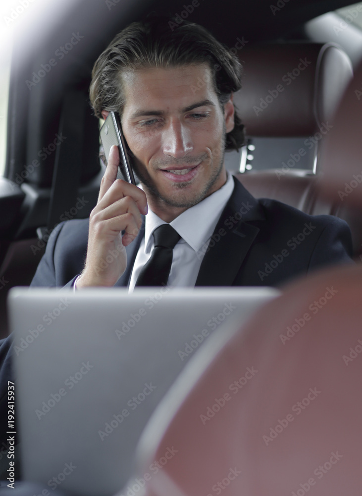 Handsome businessman using mobile phone in car.