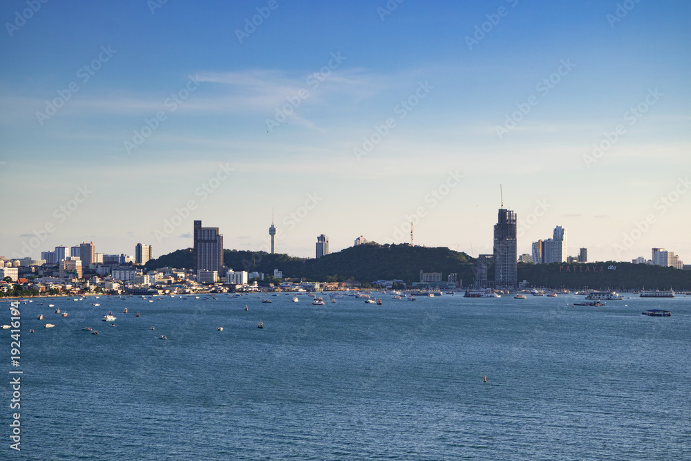 Pattaya bay in day time. Cityscape with boats, beach, buildings, mountains. Famous city in Chonburi province, Thailand.