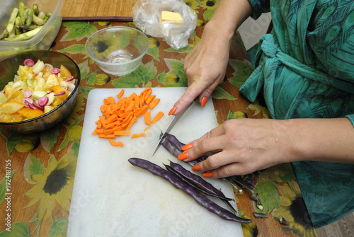 A housekeeper’s hands slicing vegetables on a chopping board