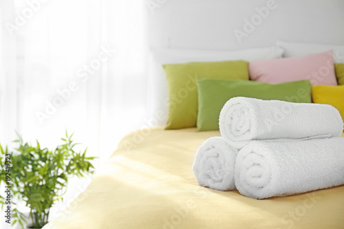 Rolled white towels on bed © Africa Studio