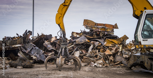 Large tracked excavator working a steel pile at a metal recycle yard