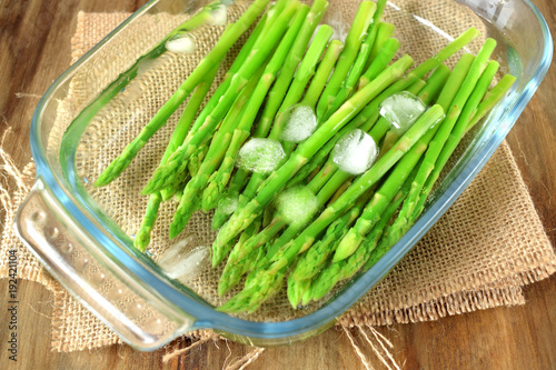 Canvas-taulu Green asparagus in cold water in a glass dish