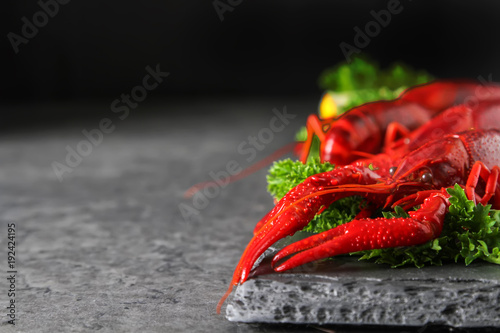 Delicious boiled crayfish close-up with lemon and parsley. Dark background. Dinner with seafood.