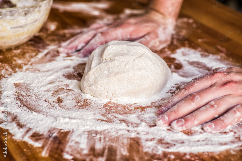 male hands kneading dough on wooden table. mass of dough on a table male hands kneading dough on wooden table. mass of dough on a table
