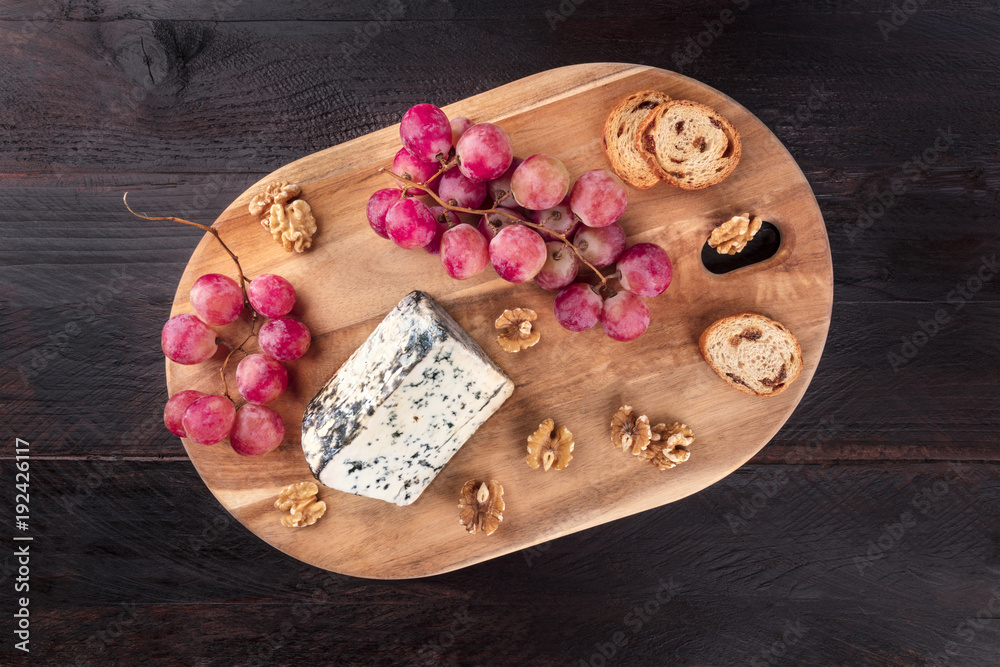 Blue cheese with grapes and copyspace on rustic textures Blue cheese with grapes and copyspace on rustic textures