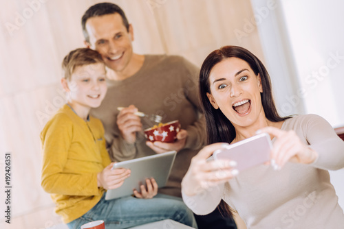 Love my boys. Upbeat young woman taking a selfie of herself and her husband and son while they having breakfast and watching something on tablet