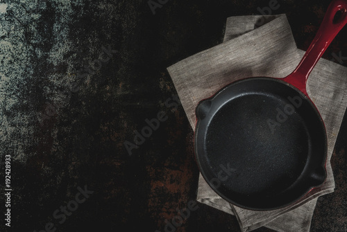 Dark rusty culinary background with empty black pan, top view copy space