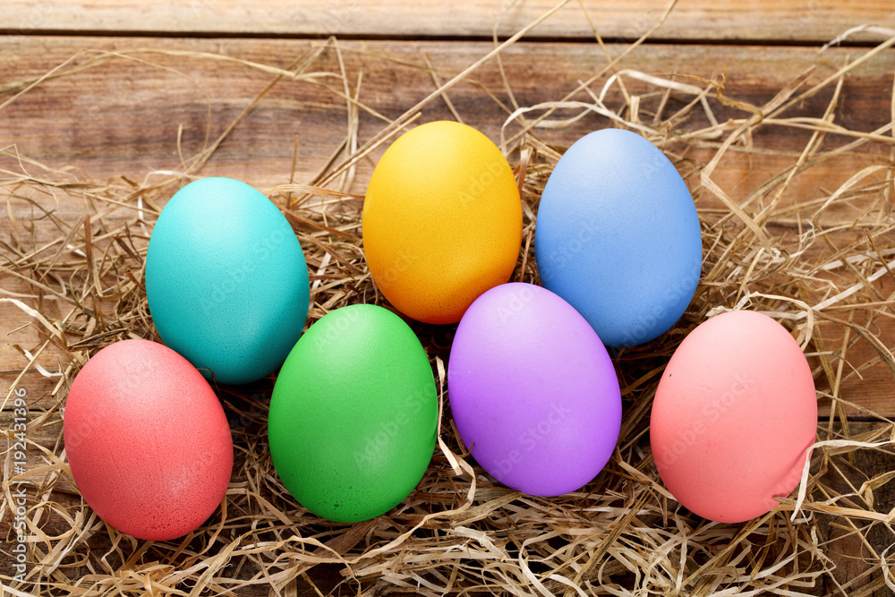 Variety of colorful easter eggs on straw and wood Variety of colorful easter eggs on straw and wood