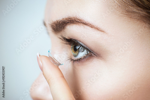 Close-up shot of young woman wearing contact lens.