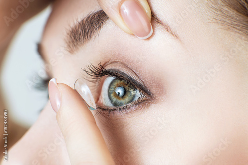 Close-up shot of young woman wearing contact lens.