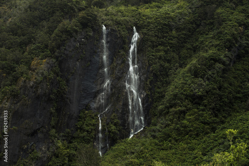Doble cascada cayendo por la ladera de una montaña llena de vegetación