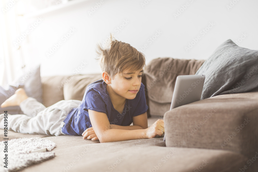 Boy on sofa playing with tablet PC Boy on sofa playing with tablet PC
