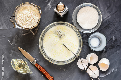 cooking of Russian dishes pancakes: eggs, milk, flour, butter, salt. Top view