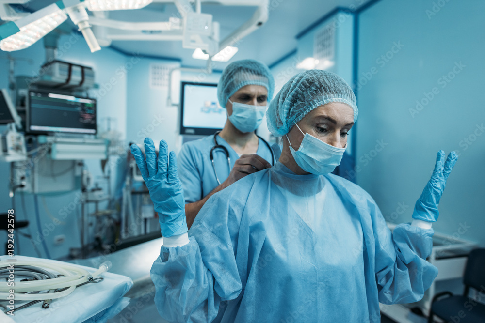 doctor helping to wear surgical uniform for surgeon doctor helping to wear surgical uniform for surgeon