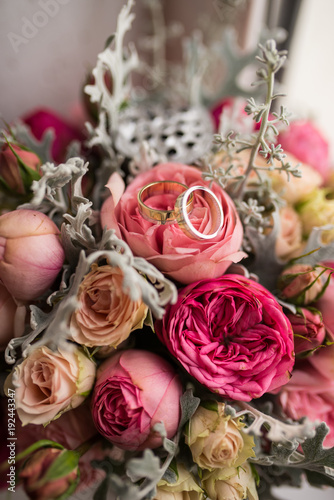 Golden wedding rings lie in a bud of pink rose. Wedding rings lie on a flower bud