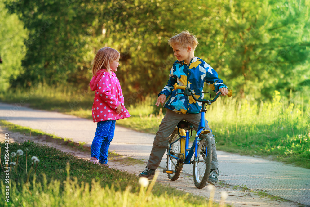happy little boy and girl riding bike in nature happy little boy and girl riding bike in nature
