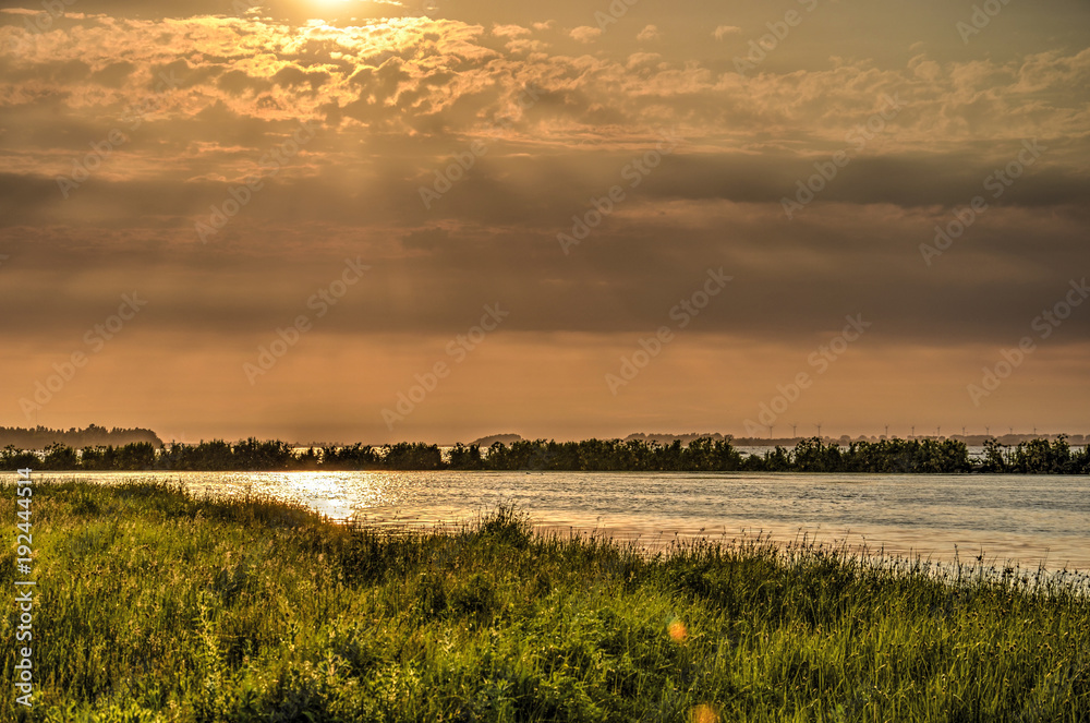 Landscape with grass and other vegetation alternated with water surfaces under a beautiful sky during the blue hour before sunset