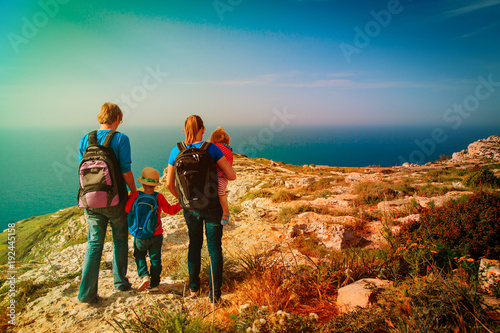 family with kids hiking in summer mountains